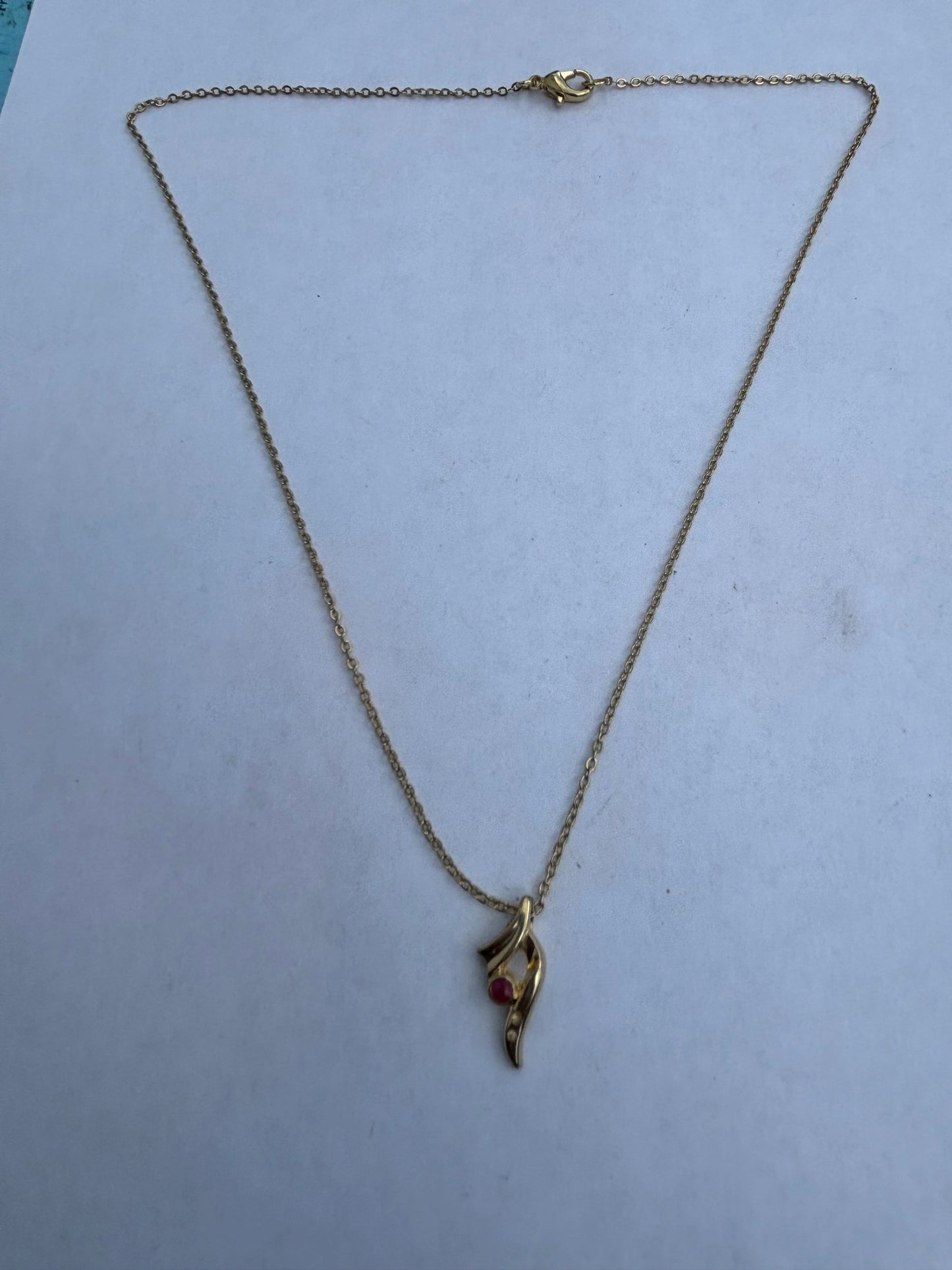 Gold chain necklace with small swoosh pendant with red and white stones