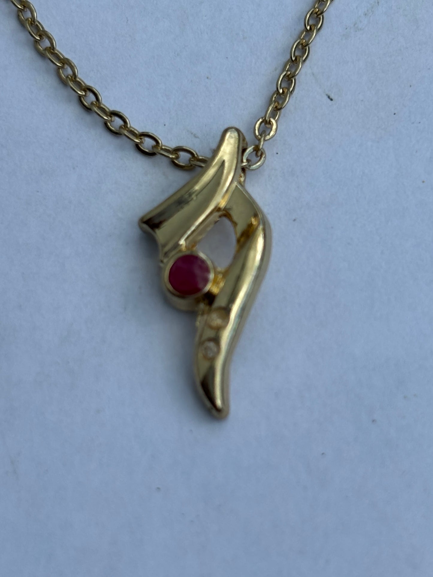 Gold chain necklace with small swoosh pendant with red and white stones