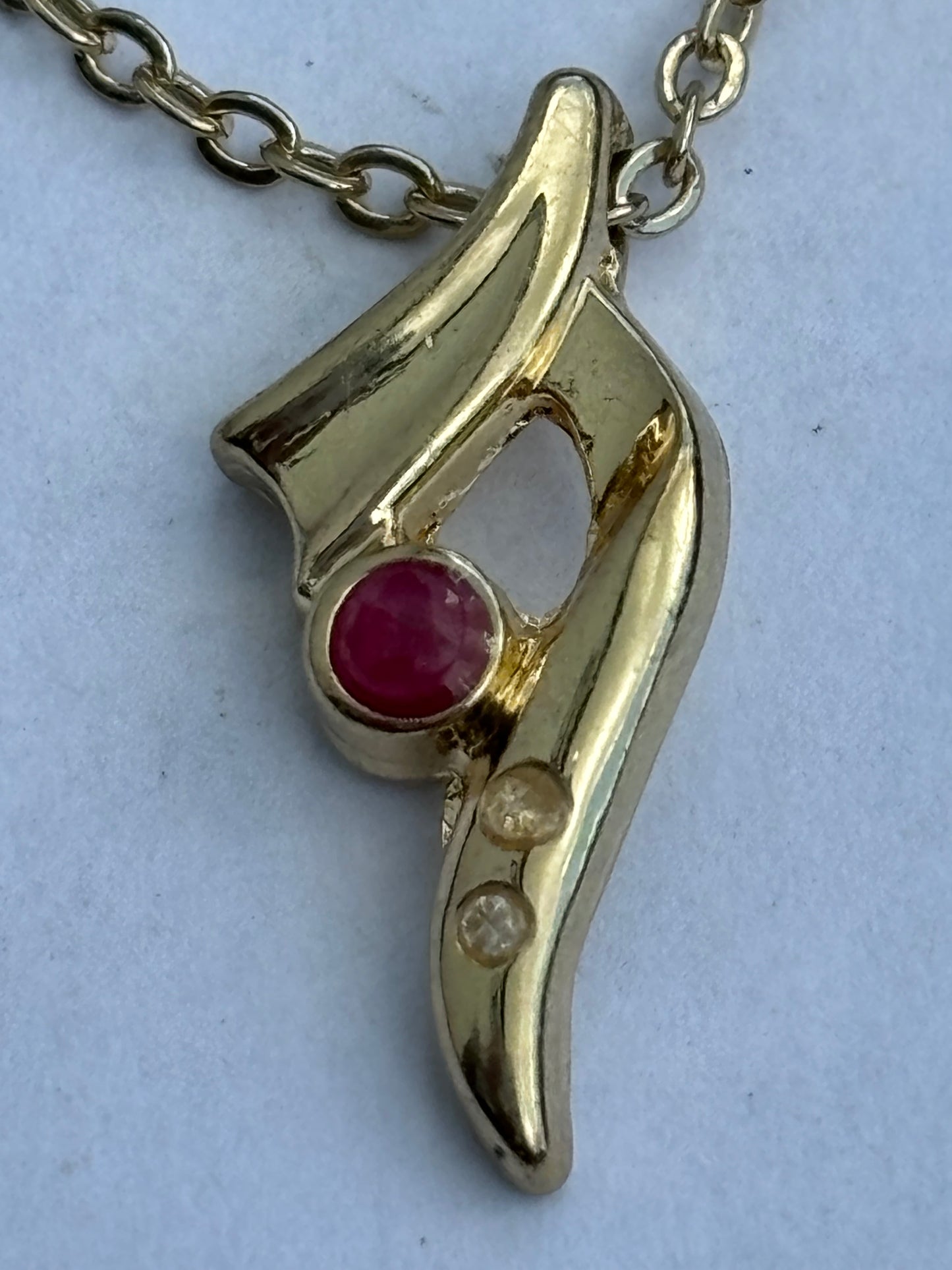 Gold chain necklace with small swoosh pendant with red and white stones