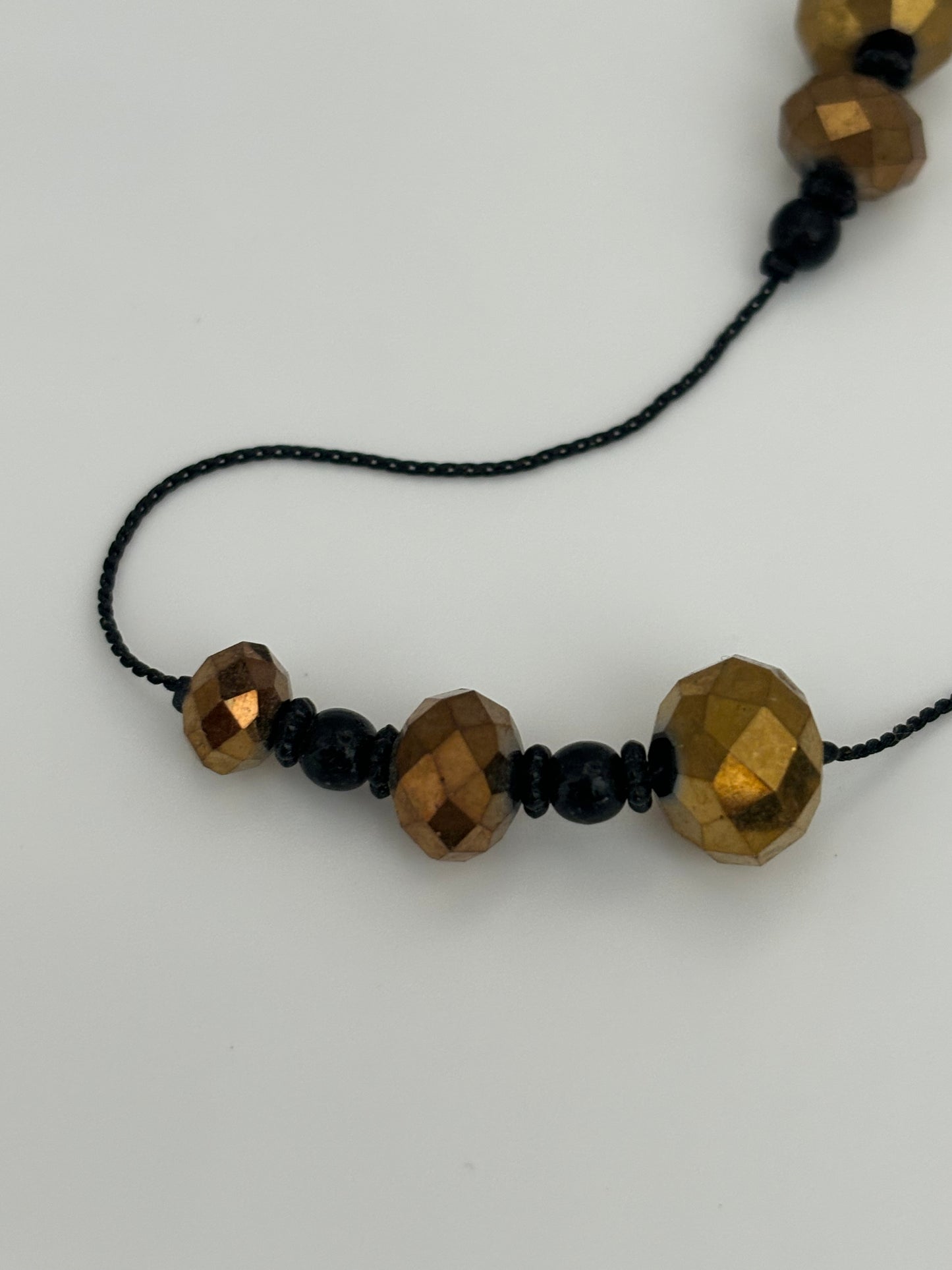 Very long black string necklace with spaced groups of gold crystal beads