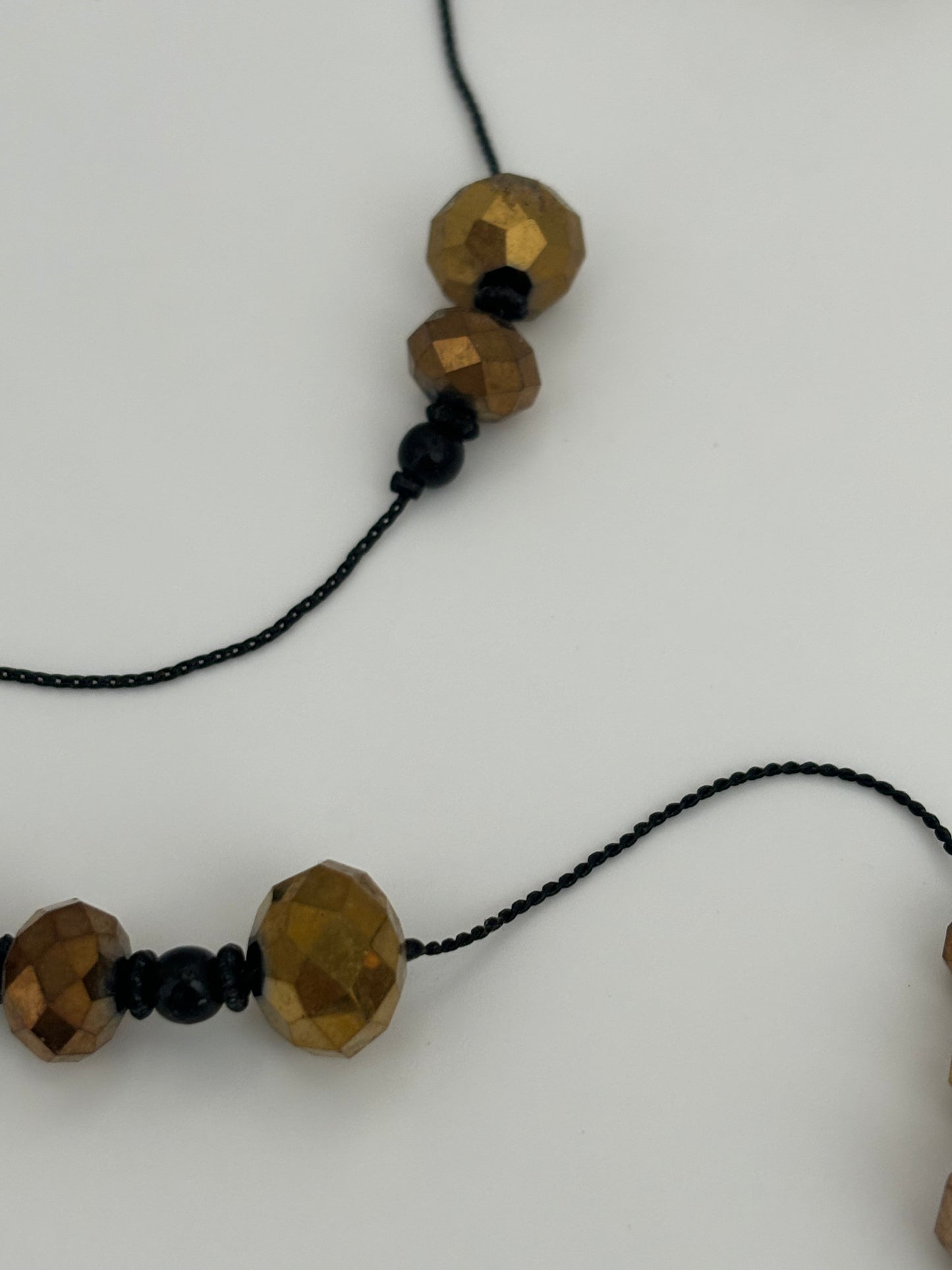 Very long black string necklace with spaced groups of gold crystal beads