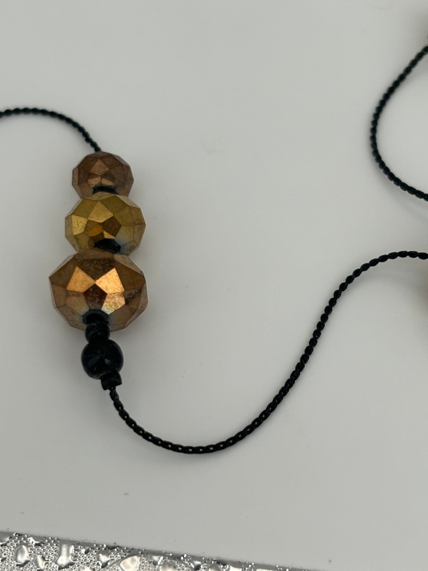 Very long black string necklace with spaced groups of gold crystal beads