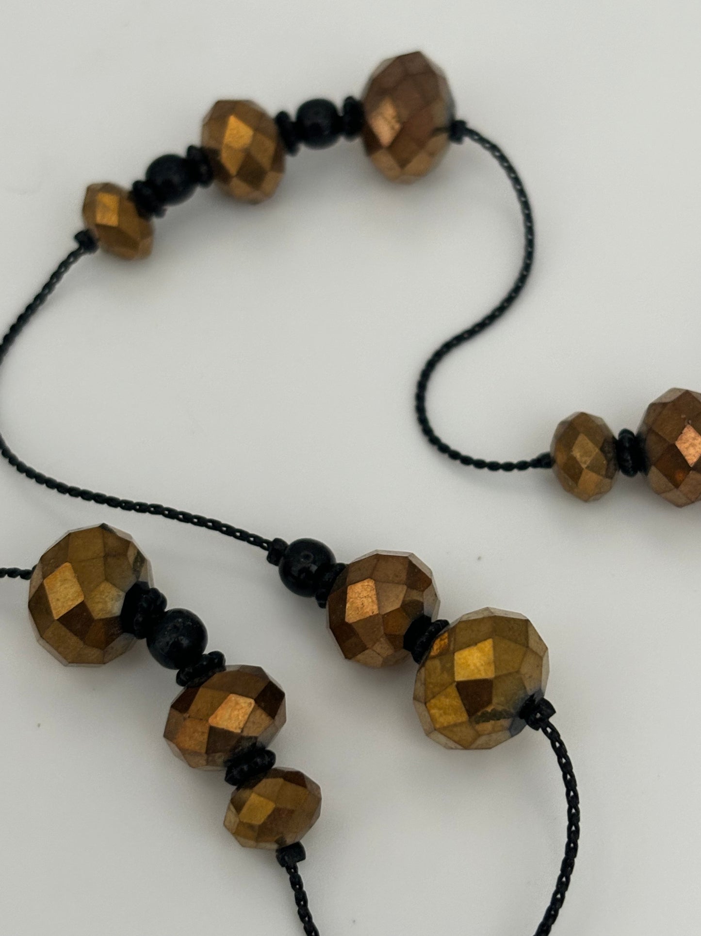 Very long black string necklace with spaced groups of gold crystal beads