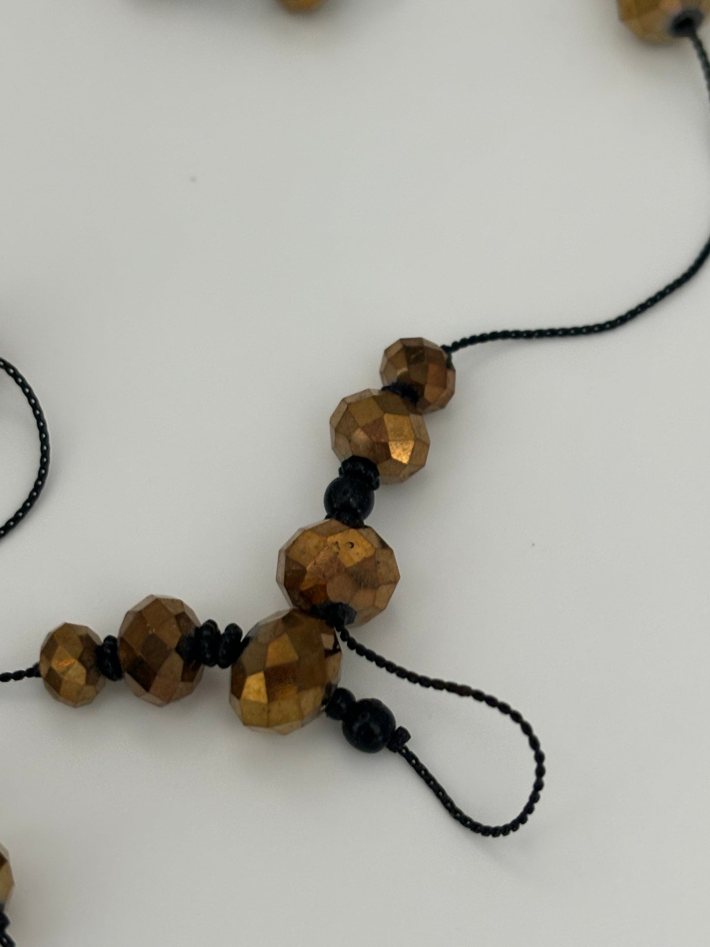 Very long black string necklace with spaced groups of gold crystal beads