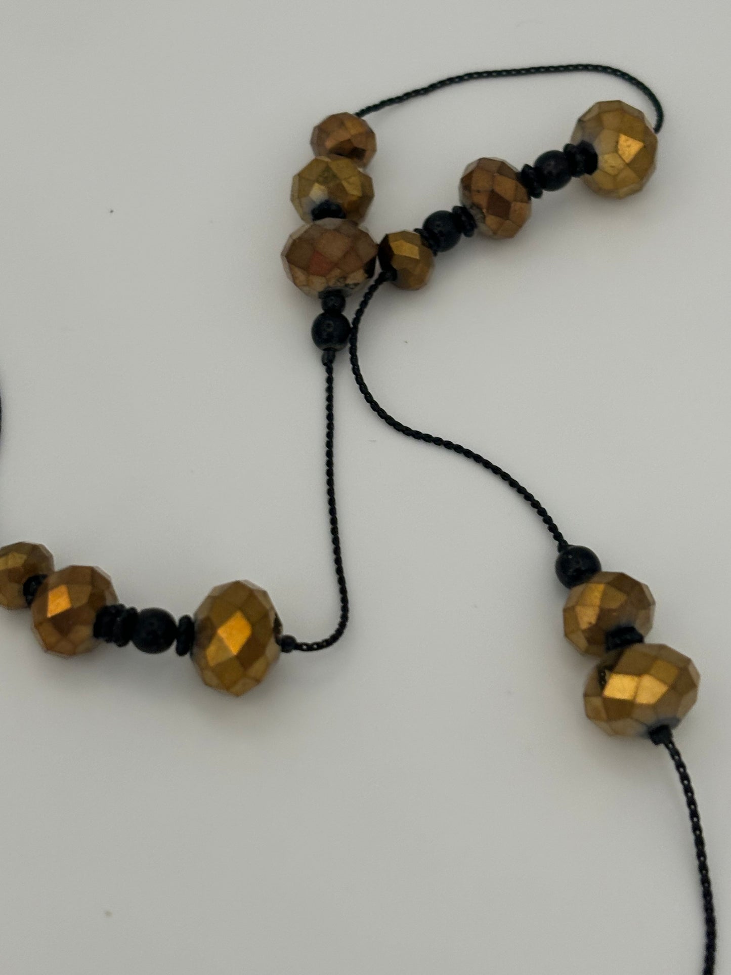 Very long black string necklace with spaced groups of gold crystal beads