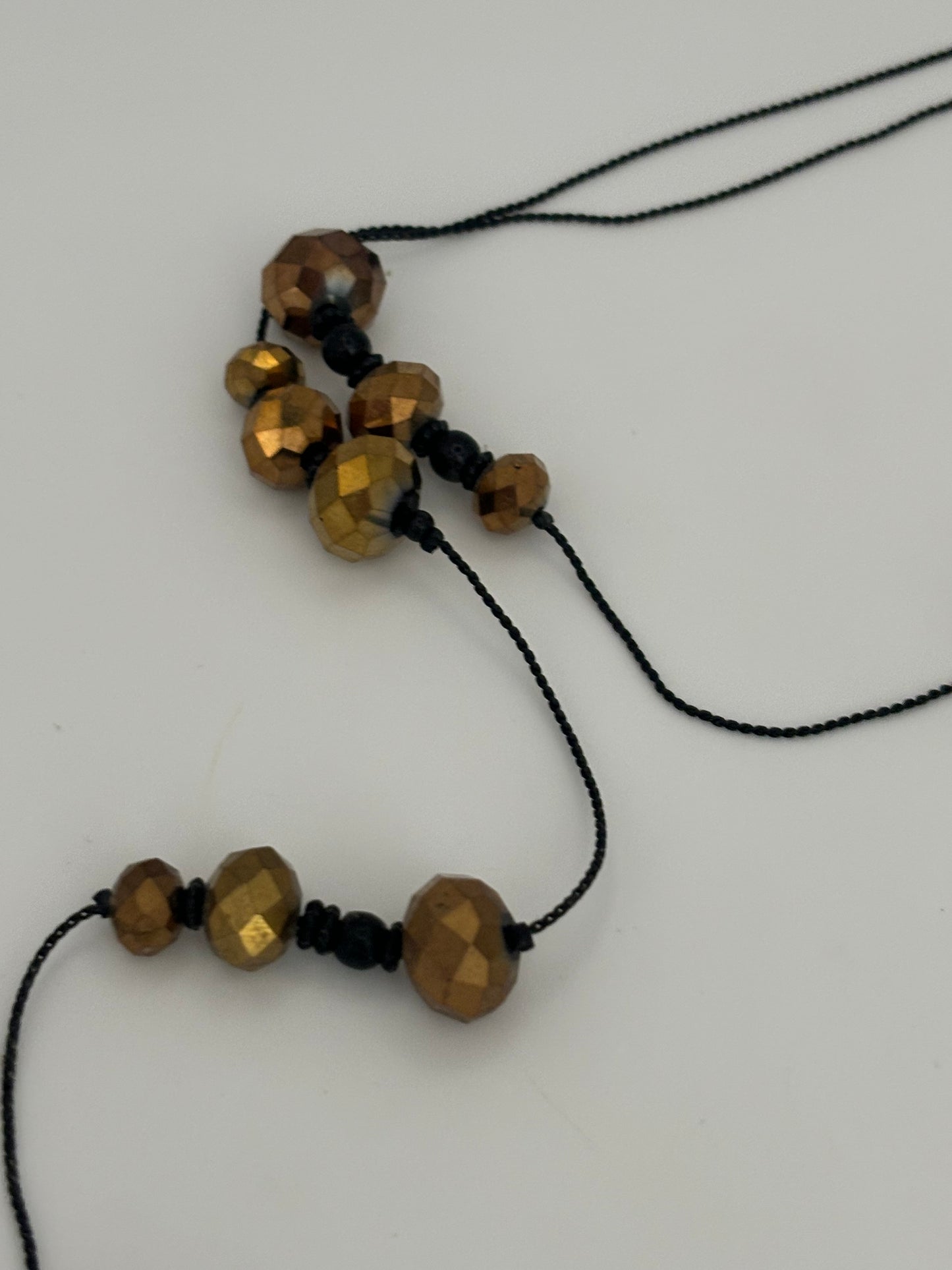 Very long black string necklace with spaced groups of gold crystal beads