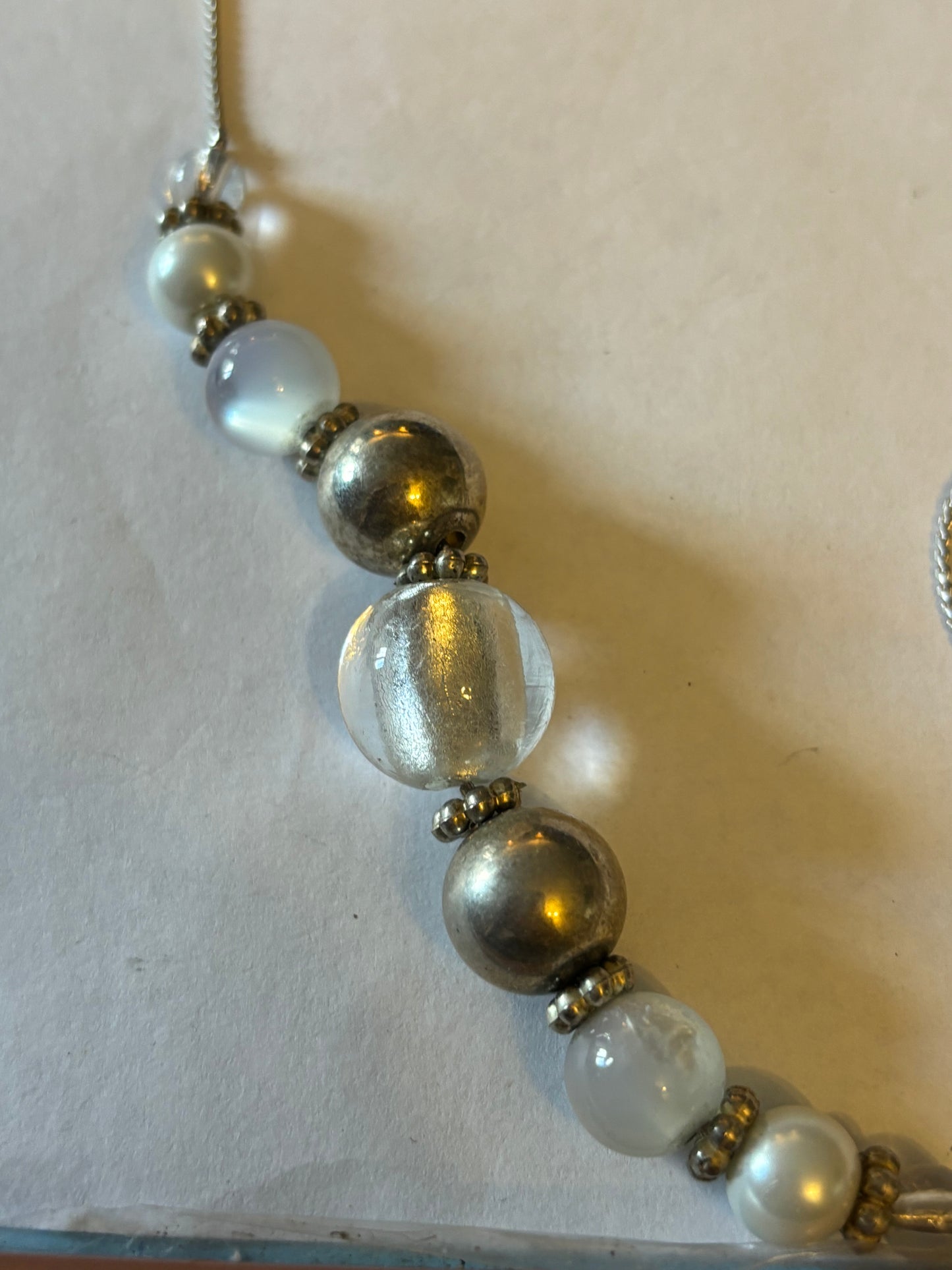 Long silver metal necklace with white, silver and pearlescent grouped beads