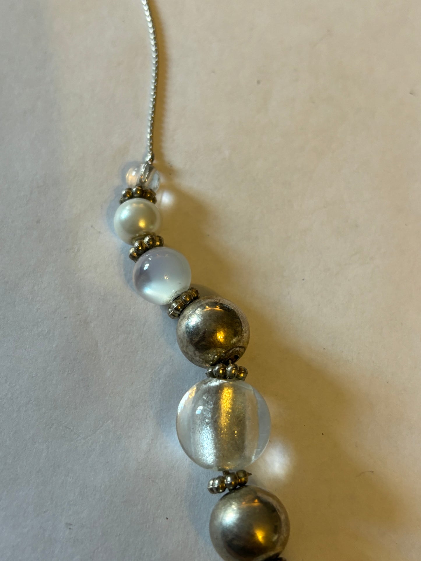 Long silver metal necklace with white, silver and pearlescent grouped beads