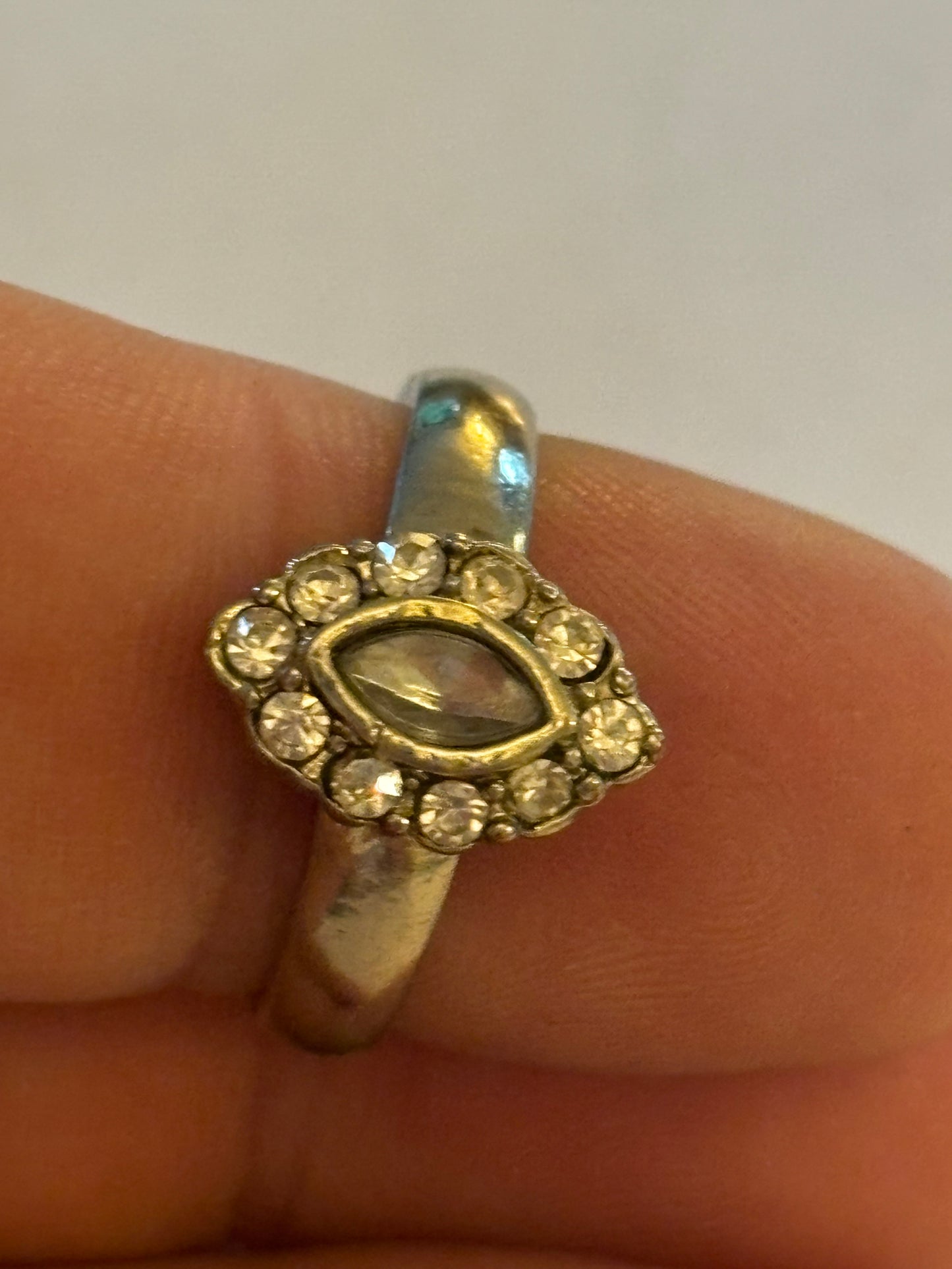 Silver ring with oval setting of small white stones surrounding larger centre