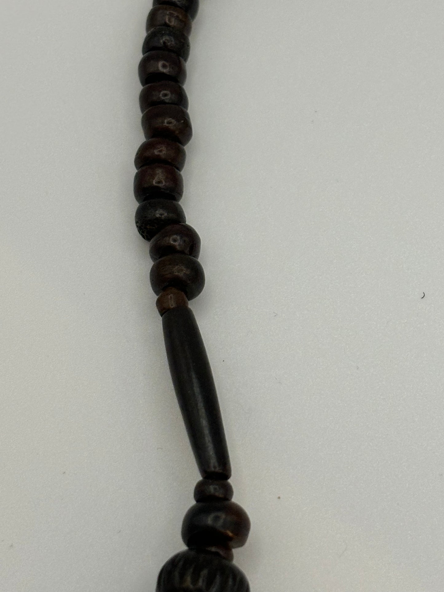 Dark brown beaded necklace with carved cylinders