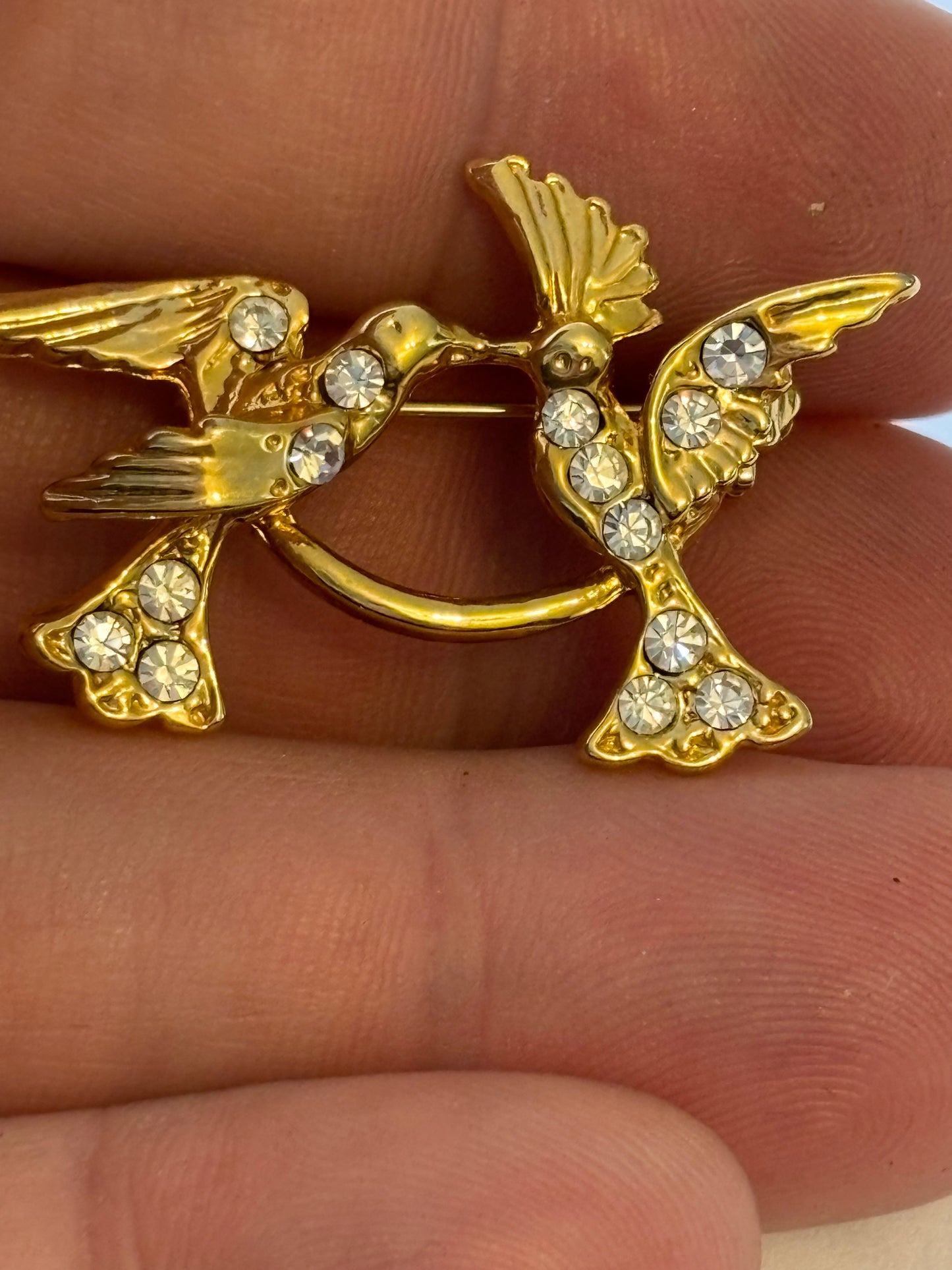 Bright gold metal brooch of two birds with diamantes