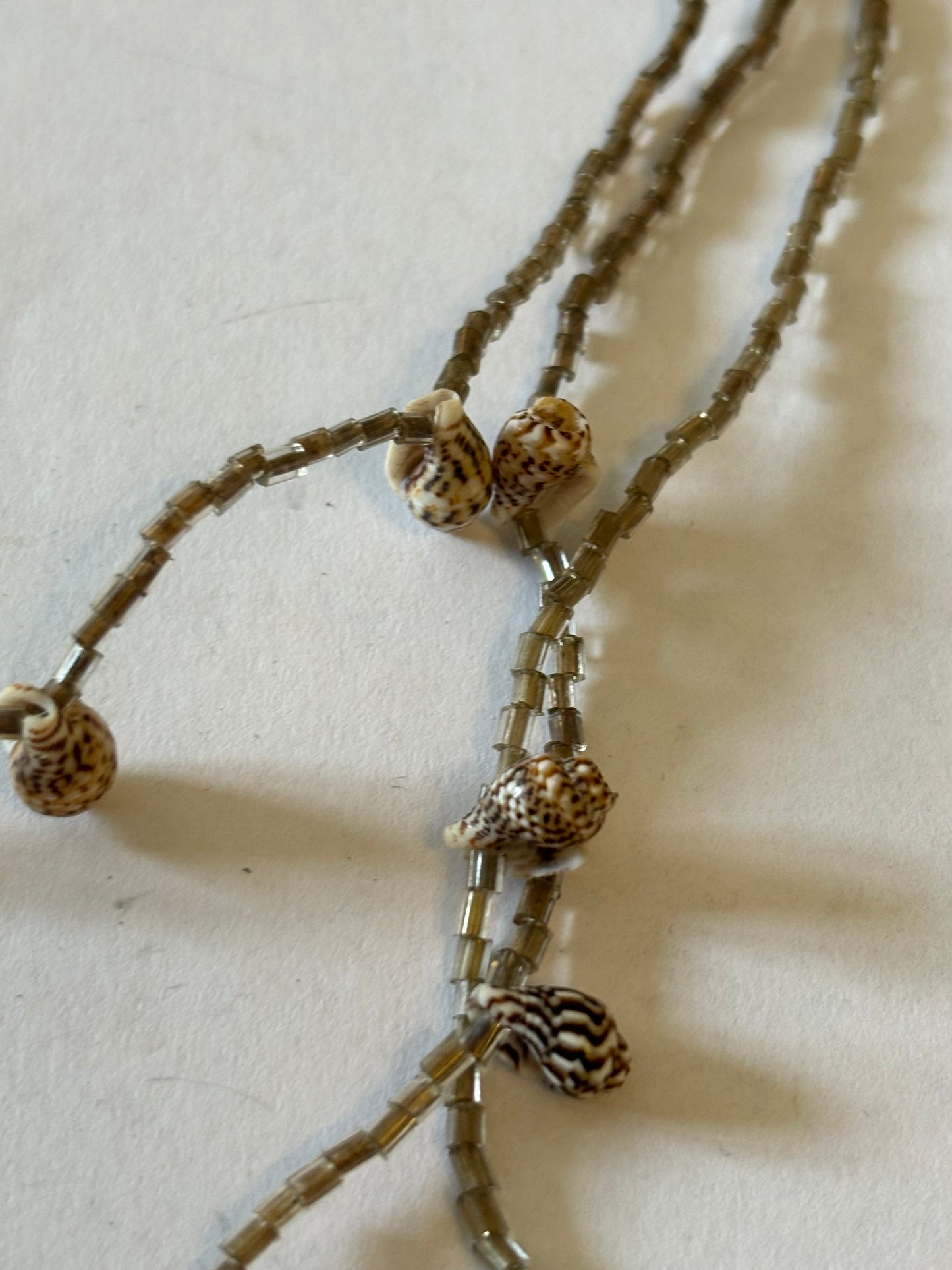 Small smokey triple tier bead necklace with very small seashells spaced along