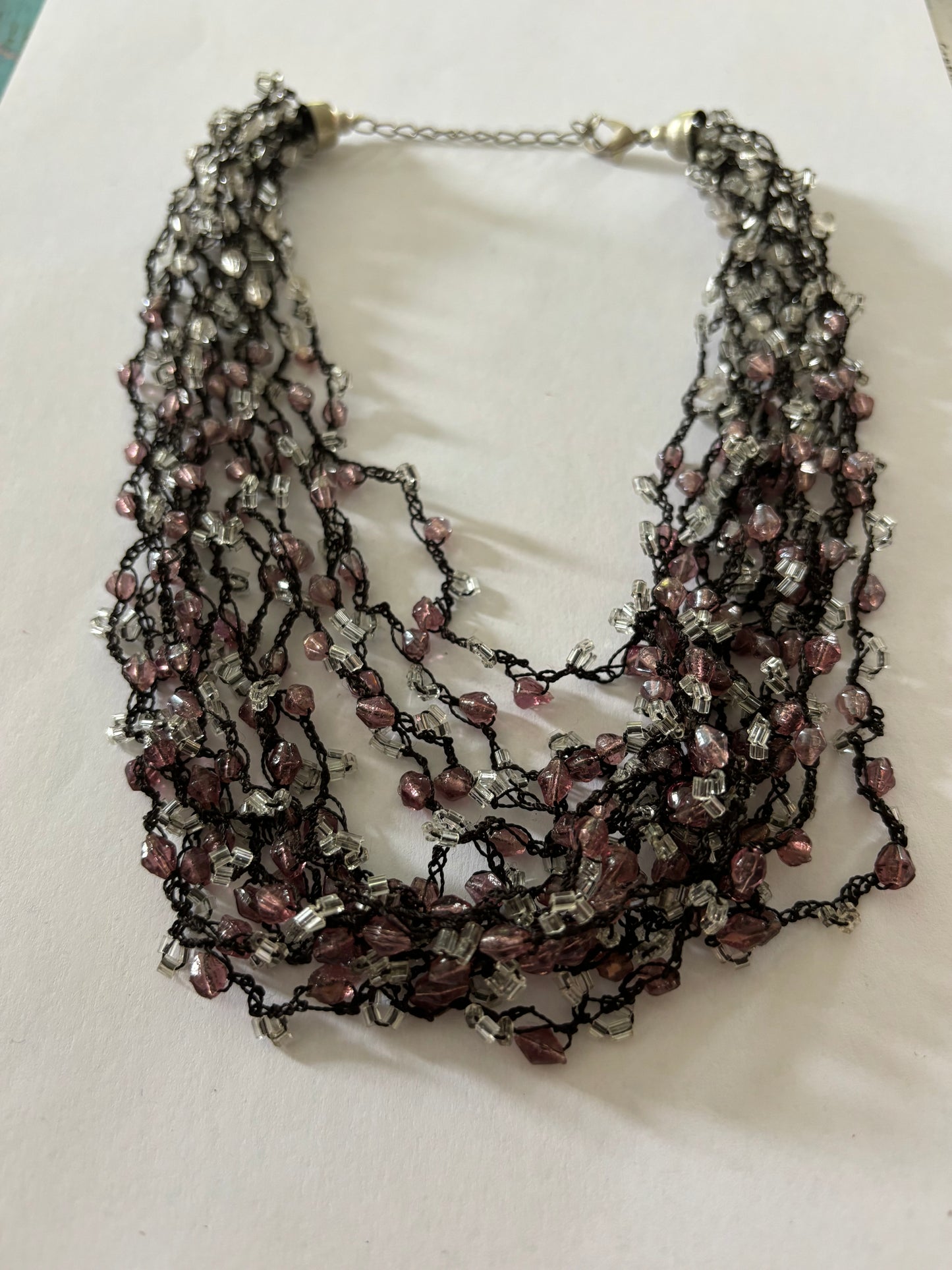 Dark metal cluster necklace of small pink/lilac and clear beads