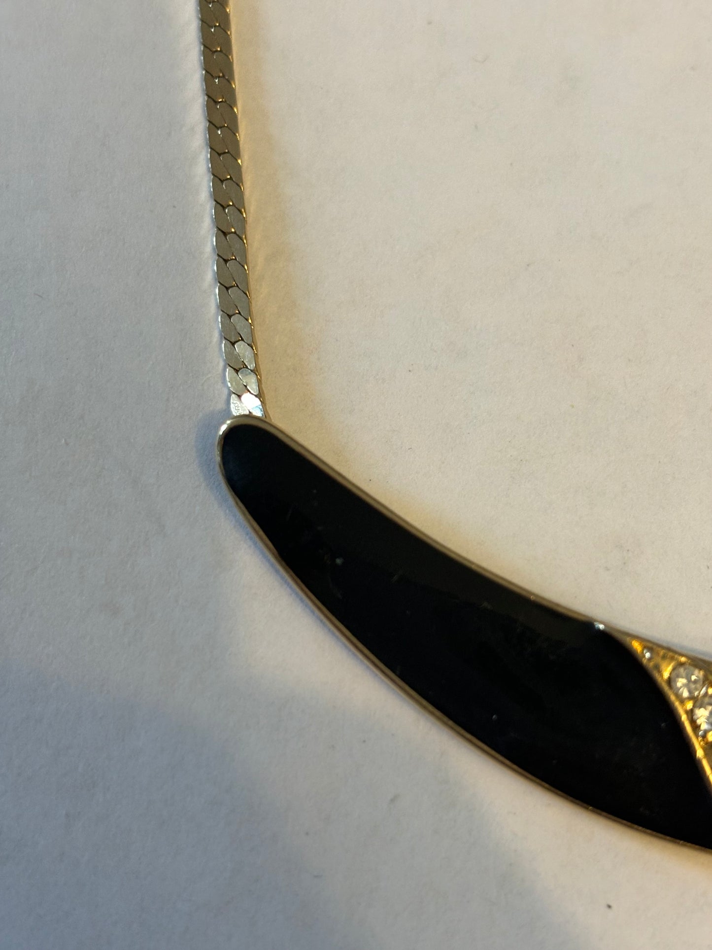 Flat gold metal necklace with curved black and diamante pendant