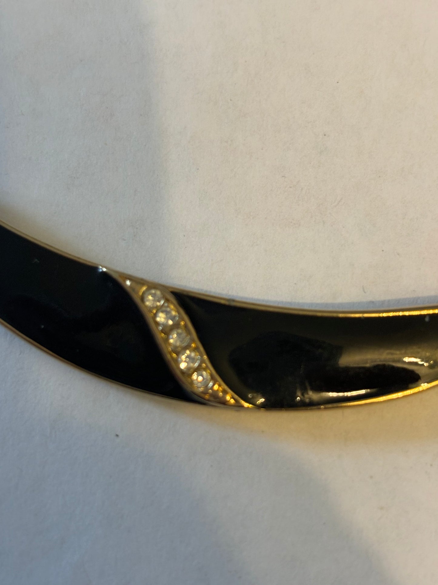 Flat gold metal necklace with curved black and diamante pendant