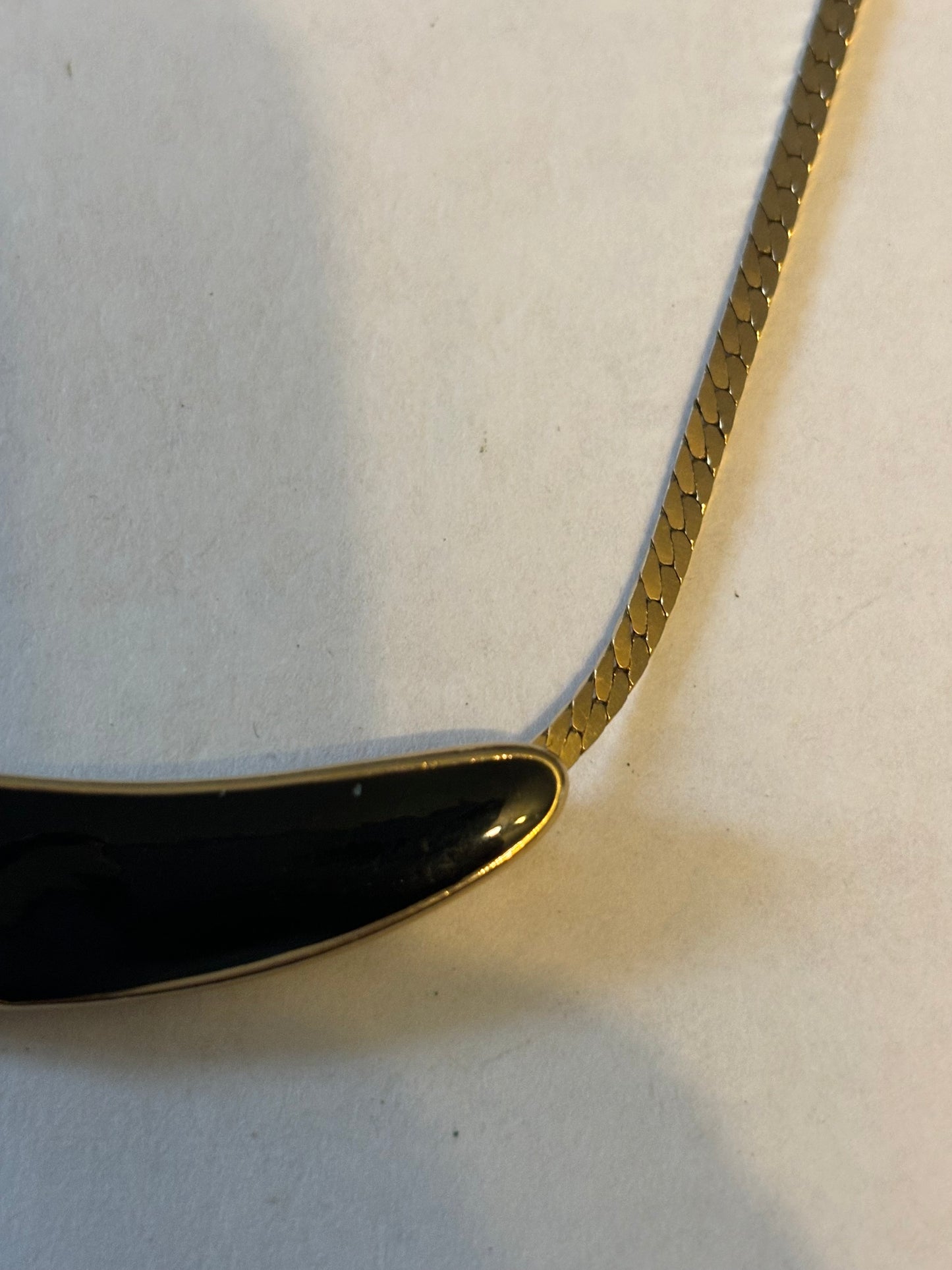 Flat gold metal necklace with curved black and diamante pendant