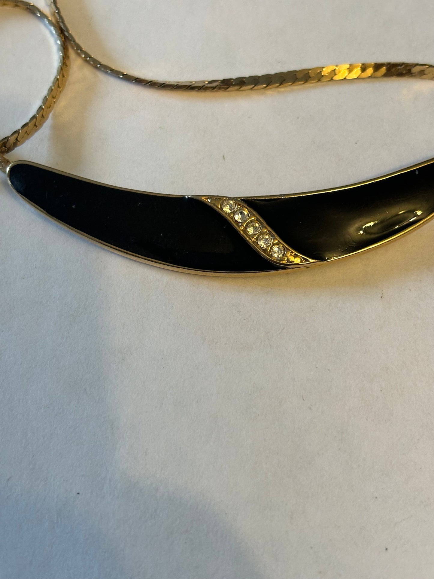 Flat gold metal necklace with curved black and diamante pendant