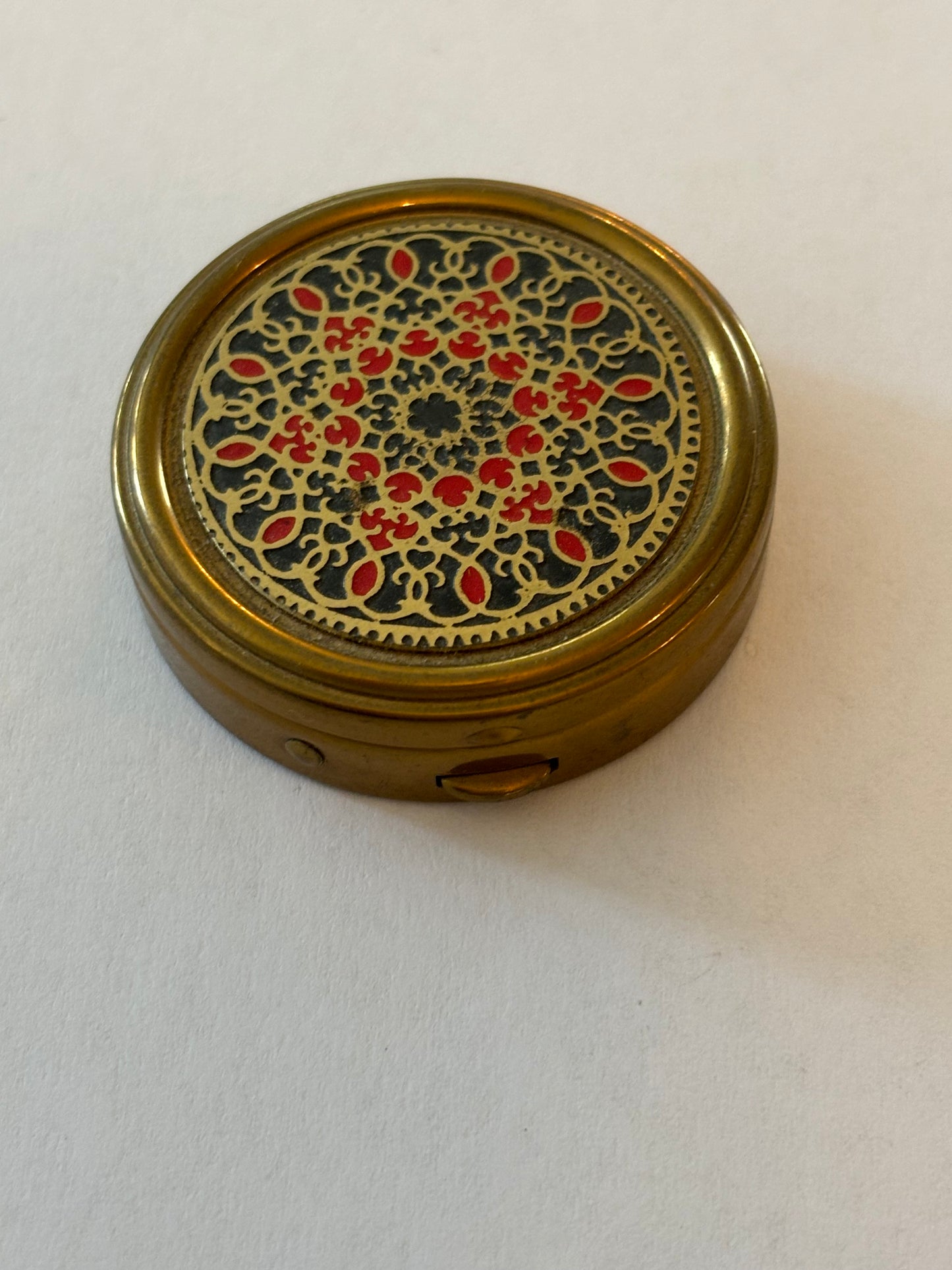 Round brass pill pot with red and gold patterned lid