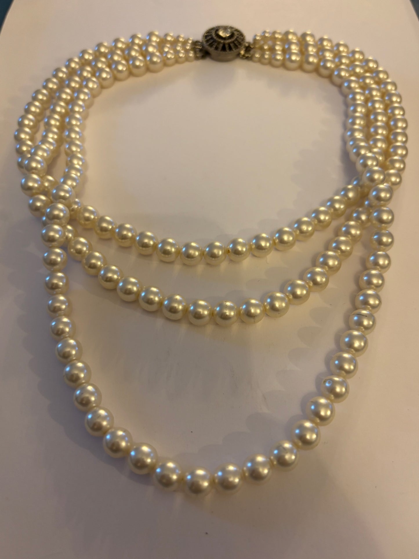 Triple tier faux pearl necklace with ornate round silver clasp