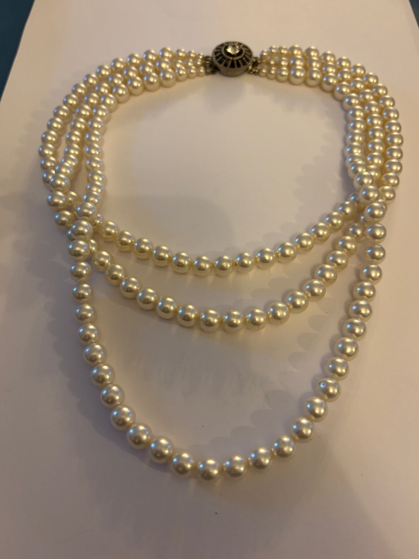 Triple tier faux pearl necklace with ornate round silver clasp