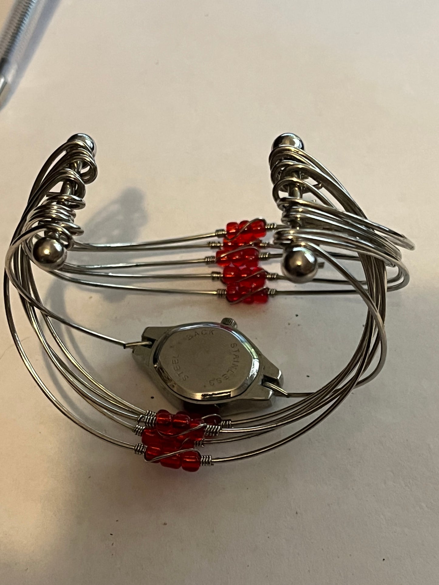 Unusual multi wire bangle with read beads and a watch