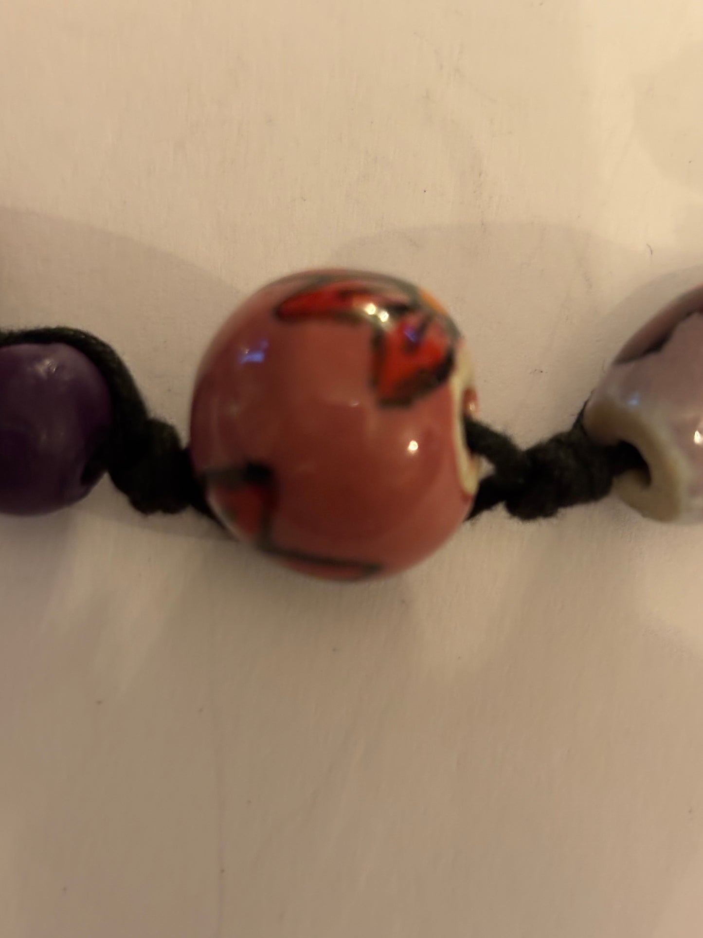 Black necklace with painted pink and purple ceramic beads