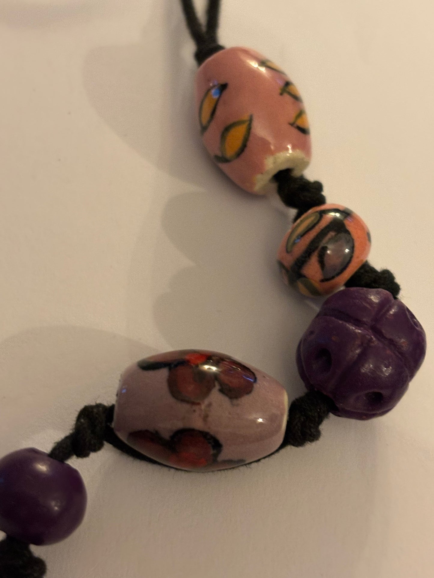 Black necklace with painted pink and purple ceramic beads