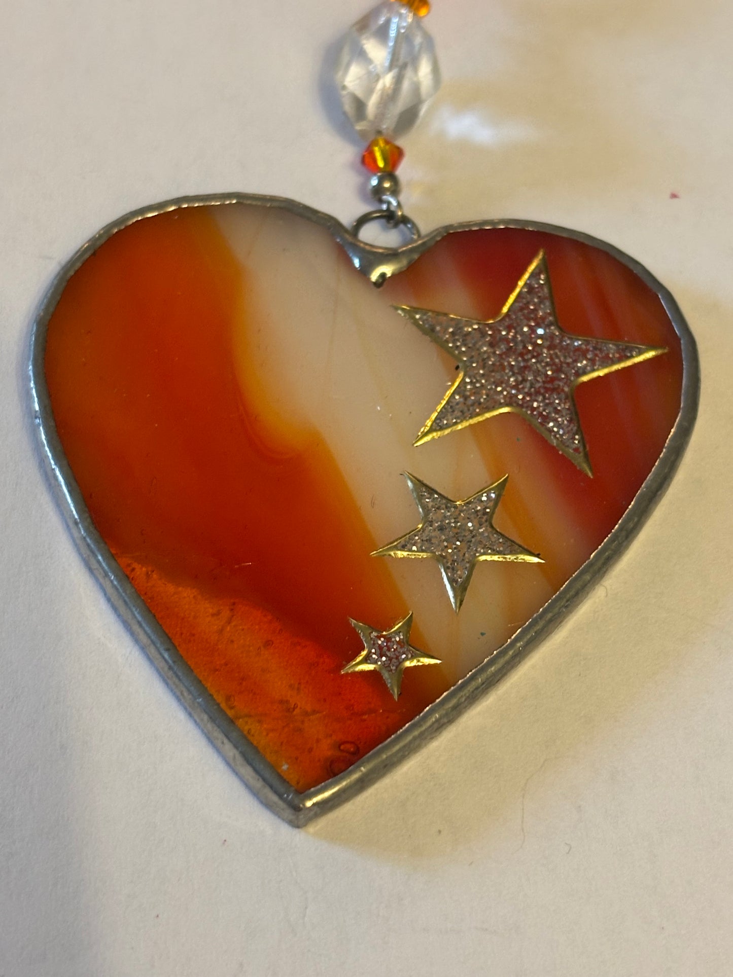 Silver metal heart ornament with orange filling and ribbon with stars