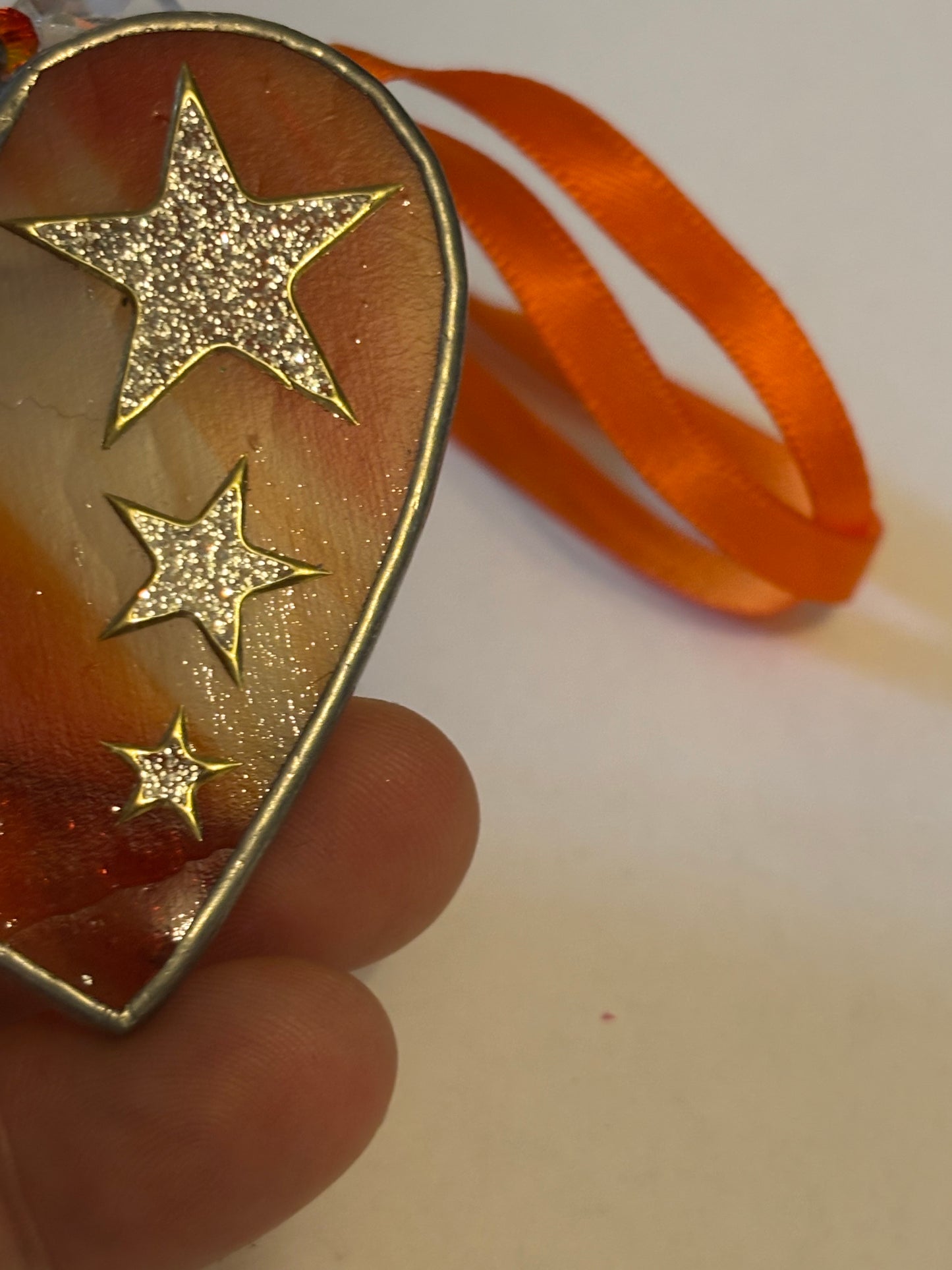 Silver metal heart ornament with orange filling and ribbon with stars