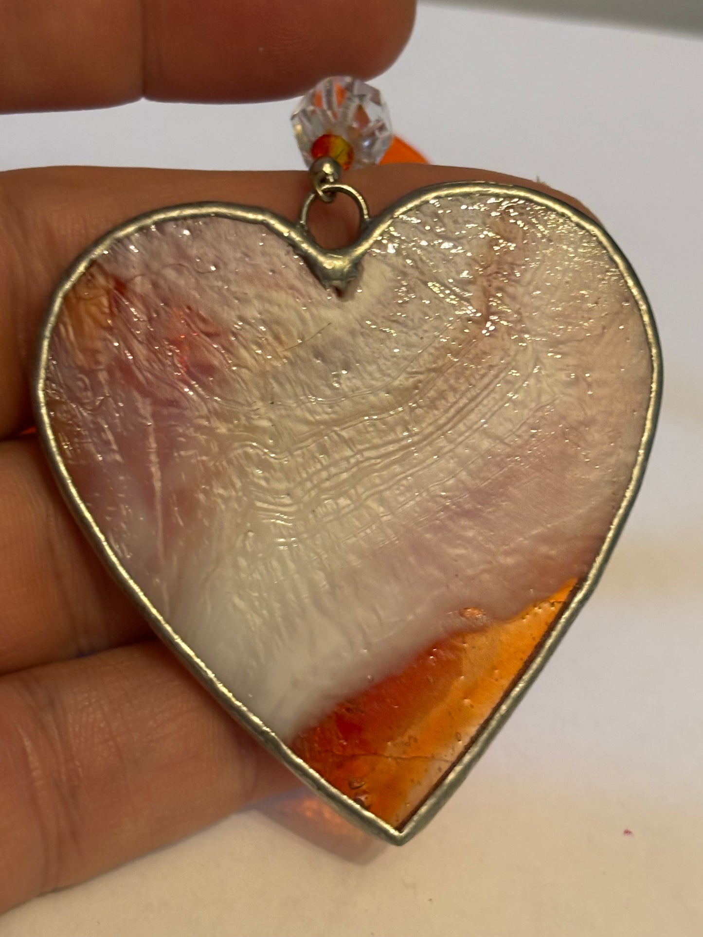 Silver metal heart ornament with orange filling and ribbon with stars