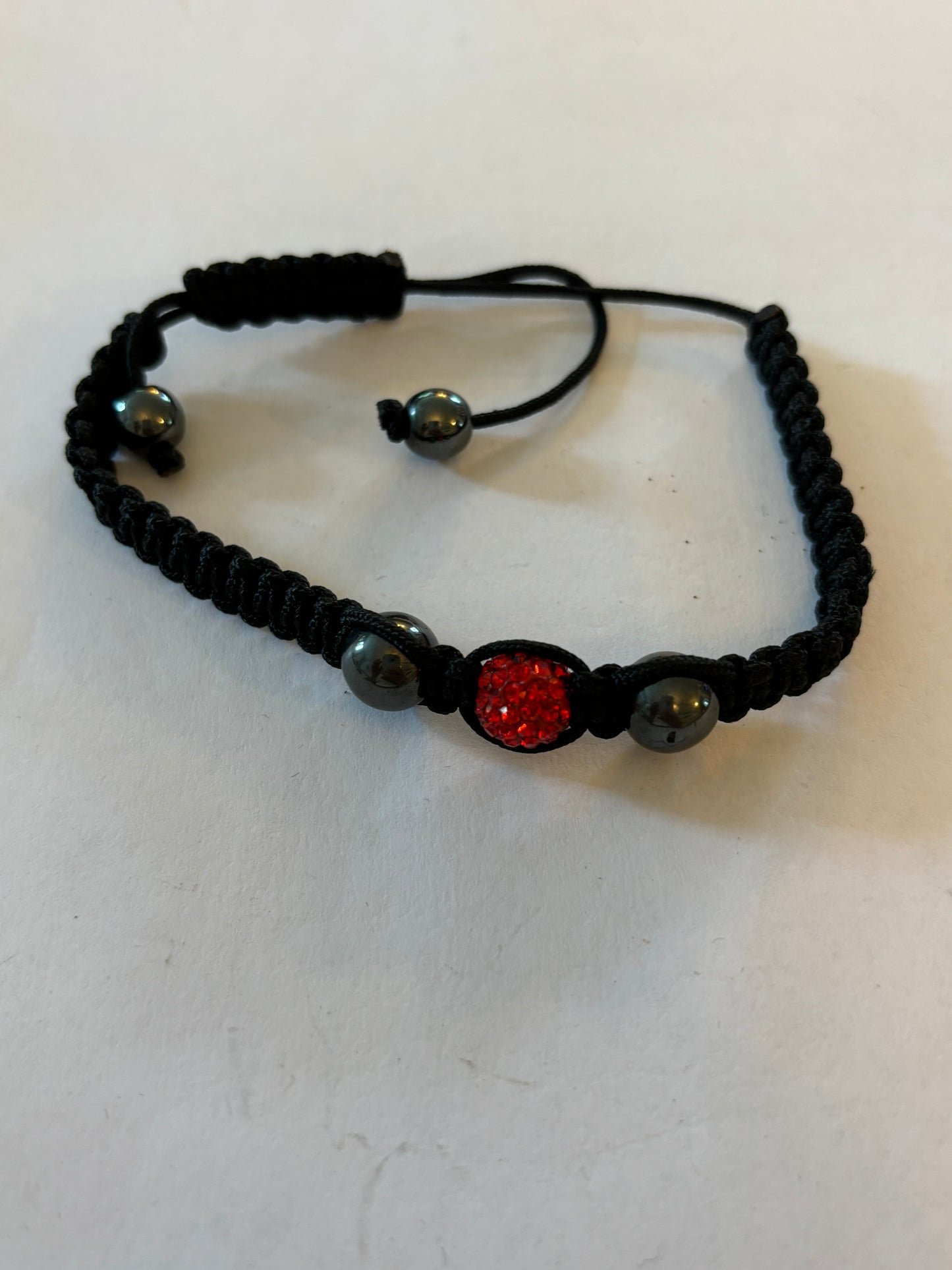 Black friendship bracelet with graphite beads and bright red diamante centre