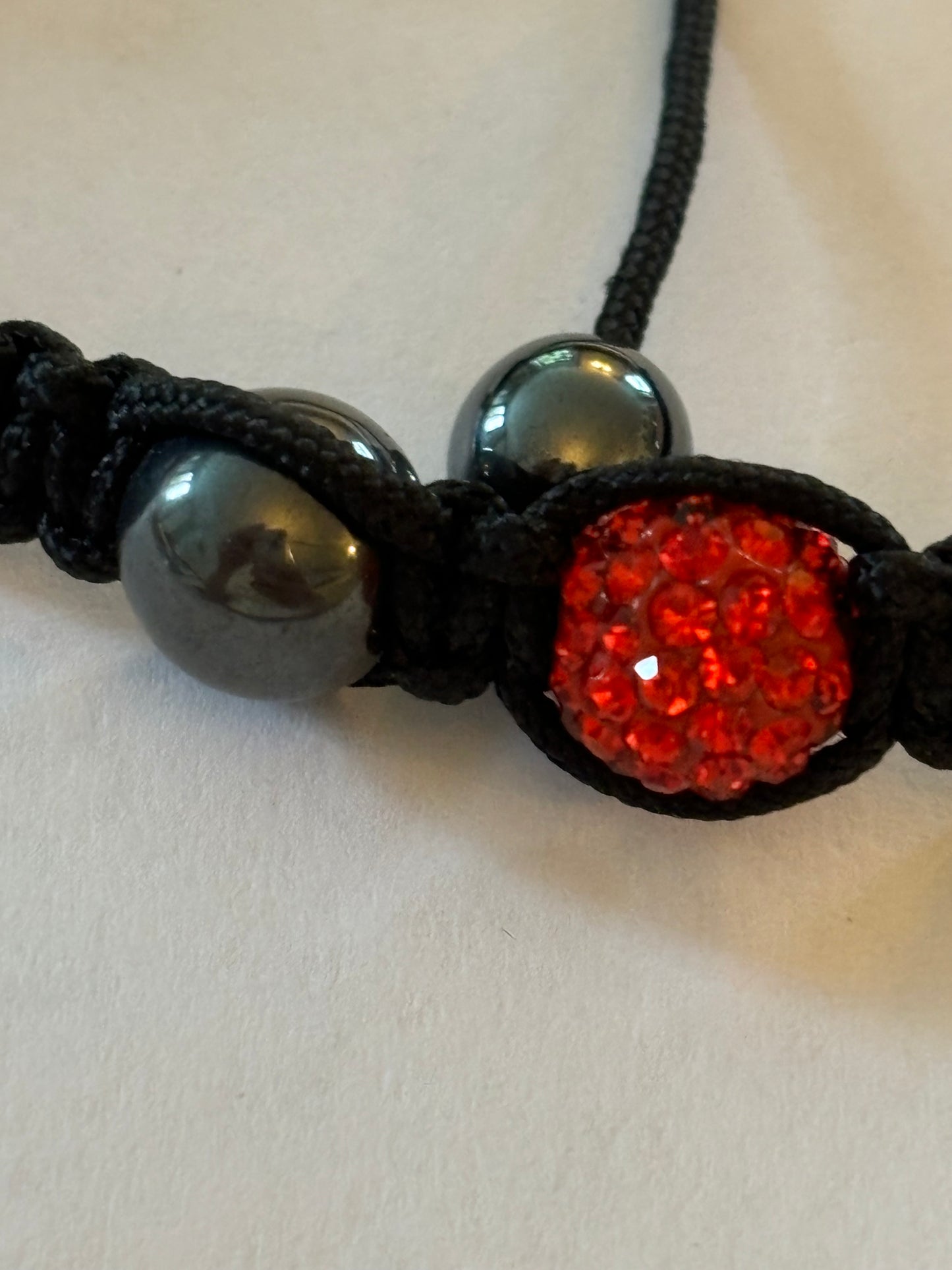 Black friendship bracelet with graphite beads and bright red diamante centre