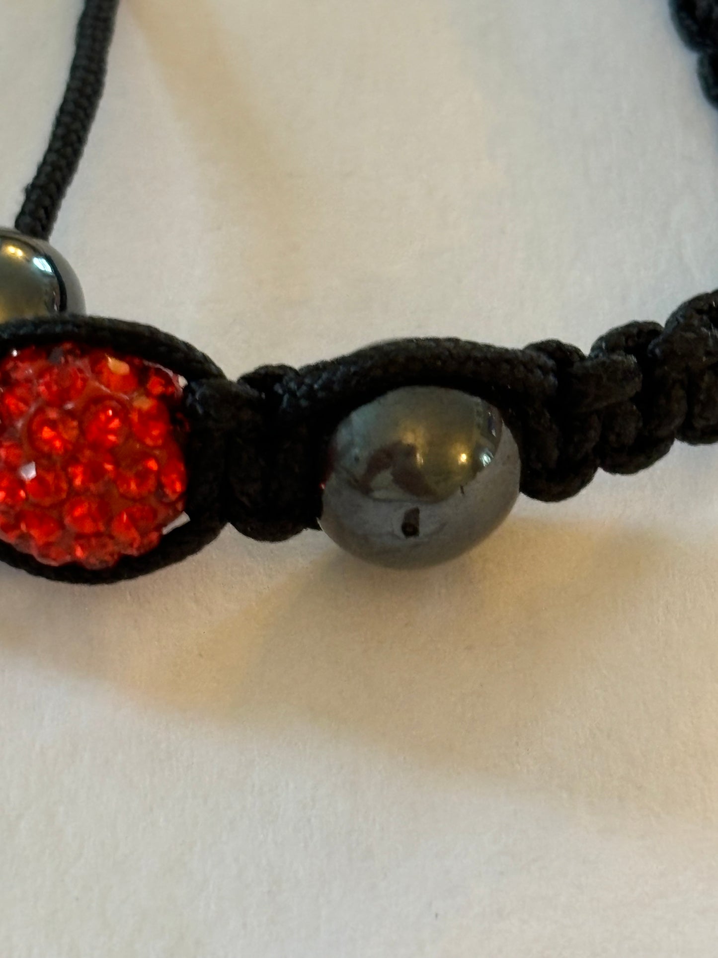 Black friendship bracelet with graphite beads and bright red diamante centre