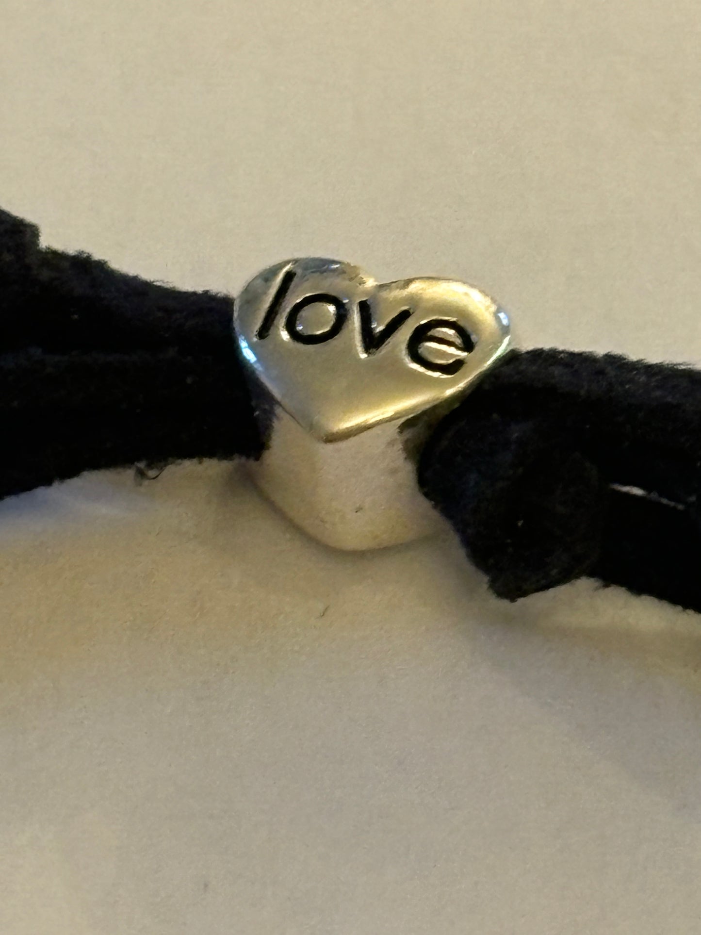 Black string friendship bracelet with silver rings and love bead