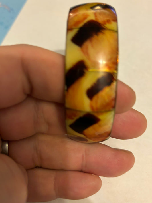 Thick metal bangle with a pearlescent yellow and brown brush pattern